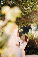 a beautiful bride stands next to a wedding dress with a boudoir attire next to a Villa in Italy.morning of the bride in Tuscany photo