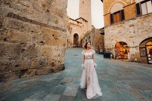 un novia en un blanco vestir en el antiguo pueblo de san gimignano.a niña camina alrededor el ciudad en italia.toscana. foto