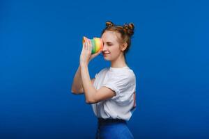 hermosa joven niña jugando con un arco iris seductor, un juguete de su infancia en un azul antecedentes foto