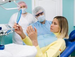 el dentista muestra el cliente el resultados de su trabajo en el espejo.el cliente sonrisas foto