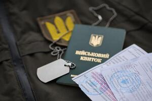 Military token or army ID ticket with mobilization notice lies on green ukrainian military uniform photo