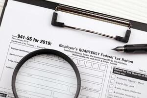 IRS Form 941-SS Employer's quarterly federal tax return blank on A4 tablet lies on office table with pen and magnifying glass photo