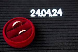 anillos de el recién casados en el antecedentes de un hermosa fecha para el Boda 24.04.2024 en un negro lettobord foto