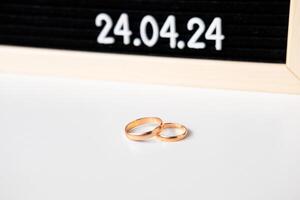 anillos de el recién casados en el antecedentes de un hermosa fecha para el Boda 24.04.2024 en un negro lettobord foto