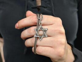 Young womans hand holding a David Star Magen David key chain. The State of Israel, Judaism, Zionism concept image. Conversion to Judaism. Passover. photo