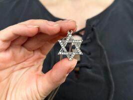 Young womans hand holding a David Star Magen David key chain. The State of Israel, Judaism, Zionism concept image. Conversion to Judaism. Passover. photo