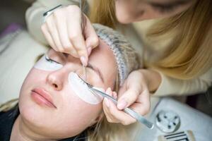 Eyelash extension procedure in beauty salon. Lashes close up. Concept spa lash. photo