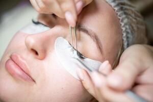 Eyelash extension procedure in beauty salon. Lashes close up. Concept spa lash. photo