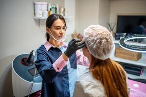 Permanent makeup cosmetologist master takes measurements for the new shape of the eyebrows of model. Microblading preparation photo