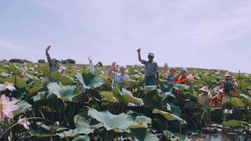 Astrakhan, Russia - August 26, 2022. A group of tourists on the lotus fields waves to the camera and smiles. Elderly tourism. Rest. video