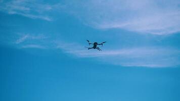 le drone mouches contre une Contexte de bleu ciel et des nuages, une vue de dessous. le quadcopter avec le caméra plane à une faible altitude. rotation rapide drone hélices. video