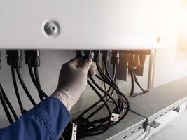A engineering checking string cable lines in inverter solar panel.The Hand hold a string cable for check and repair. Inverter service concept for technology  background. photo