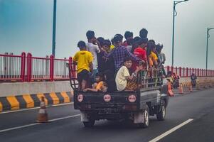 A small pick-up truck filled with many teenage boys in its cart was passing on the Suramadu bridge, indonesia, 17 November 2023. photo