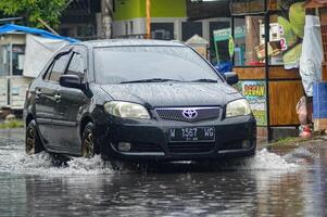 A Toyota Vios car that crashed through floodwater during heavy rain on a residential street, Indonesia, 8 December 2023. photo