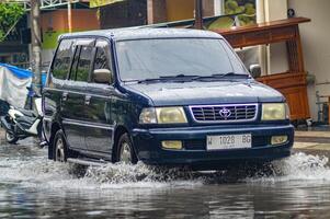 un toyota kijang coche ese rompió mediante agua de inundación durante pesado lluvia en un residencial calle, Indonesia, 8 diciembre 2023. foto