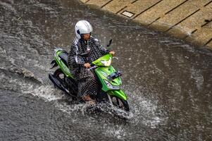 a motorcyclist who drove through flood waters during heavy rain in a residential area, Indonesia, 8 December 2023. photo