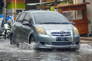 A Toyota Yaris crashed into a flood during heavy rain on a residential street, Indonesia, 8 December 2023. photo