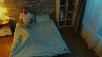 superiore Visualizza di uomo nel pigiami Lavorando su il computer portatile in ritardo notte nel letto video