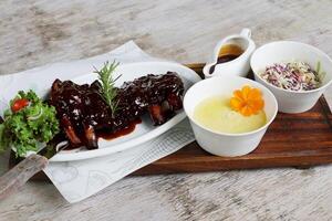 Full Slab BBQ Baby Back Ribs with sauce and salad served in a dish isolated on grey background side view photo