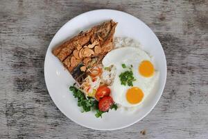 bailando n / A bangus con soleado huevo y arroz con tomate con ensalada servido en plato aislado en de madera antecedentes parte superior ver de desayuno foto