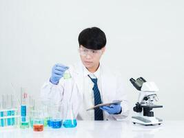 Portrait asian man student scientist doctor in shirt gown one person wokk job plant looking hand holding control microscope on white table see the results of scientific experiments inside laboratory photo