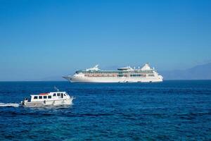 Boat and cruise liner is Aegean sea. Chora, Mykonos island, Greece photo