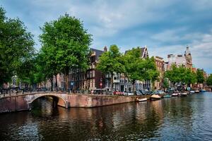 Amsterdam view   canal with boad, bridge and old houses photo