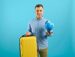 Excited traveler tourist man isolated on blue background. Passenger traveling abroad on weekends. Air flight journey concept. Holding world globe. photo