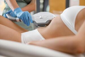 Closeup of young woman getting laser epilation with ipl machine in beauty center photo