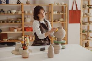 Professional female ceramist work with unfired clay vase in pottery studio. High quality photo