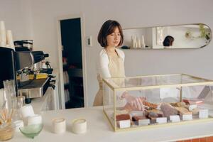 Female waitress's hand puts the piece of cupcake on the table at a cafe standing behind bar counter photo