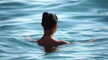 mujer nadando en calma mar a atardecer, camara lenta, espalda vista. concepto de cuerpo imagen y aptitud física, disfrutando un sereno playa. contento mujer con Perfecto ajuste cuerpo disfruta mar playa video