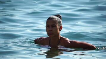 Woman swimming in calm sea at sunset, slow-motion, back view. Concept of body image and fitness, enjoying a serene beach. Happy woman with perfect fit body enjoys sea beach video