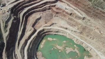 aéreo ver industrial de a cielo abierto minería cantera con un montón de maquinaria a trabajo - extrayendo flujos para el metal industria. oval minería industrial cráter, ácido mía drenaje en roca. video