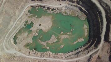 aéreo ver industrial de a cielo abierto minería cantera con un montón de maquinaria a trabajo - extrayendo flujos para el metal industria. oval minería industrial cráter, ácido mía drenaje en roca. video