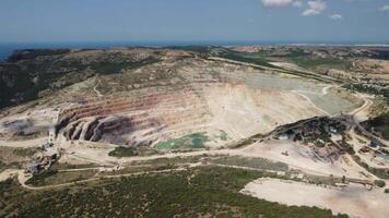 aéreo ver industrial de a cielo abierto minería cantera con un montón de maquinaria a trabajo - extrayendo flujos para el metal industria. oval minería industrial cráter, ácido mía drenaje en roca. video