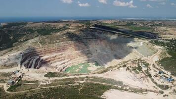 aéreo ver industrial de a cielo abierto minería cantera con un montón de maquinaria a trabajo - extrayendo flujos para el metal industria. oval minería industrial cráter, ácido mía drenaje en roca. video