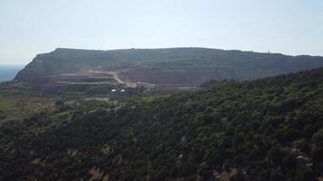 aéreo ver de industrial a cielo abierto minería cantera con un montón de maquinaria a trabajo - extrayendo flujos para el metal industria. oval minería industrial cráter, ácido mía drenaje en roca. video