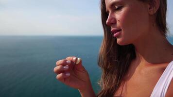 Woman eating milky almond nuts. A young caucasian woman eating fresh almond after morning fitness yoga near sea. Healthy vegan food. Slow motion video