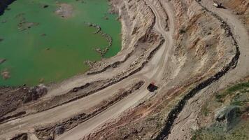 Aerial view of industrial opencast mining quarry with lots of machinery at work - extracting fluxes for the metal industry. Oval mining industrial crater, acid mine drainage in rock. video