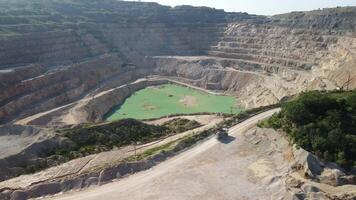 Aerial view of industrial opencast mining quarry with lots of machinery at work - extracting fluxes for the metal industry. Oval mining industrial crater, acid mine drainage in rock. video