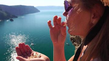 vrouw aan het eten melkachtig amandel noten. een jong Kaukasisch vrouw aan het eten vers amandel na ochtend- geschiktheid yoga in de buurt zee. gezond veganistisch voedsel. langzaam beweging video