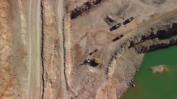 Aerial view of industrial opencast mining quarry with lots of machinery at work - extracting fluxes for the metal industry. Oval mining industrial crater, acid mine drainage in rock. video