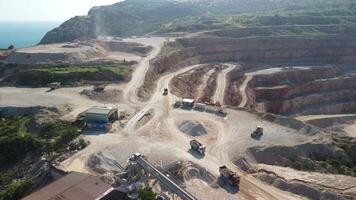 Aerial view of industrial opencast mining quarry with lots of machinery at work - extracting fluxes for the metal industry. Oval mining industrial crater, acid mine drainage in rock. video