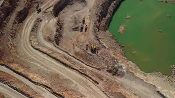 aéreo ver de industrial a cielo abierto minería cantera con un montón de maquinaria a trabajo - extrayendo flujos para el metal industria. oval minería industrial cráter, ácido mía drenaje en roca. video