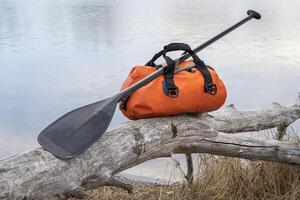 waterproof duffel and stand up paddle on a lake shore photo