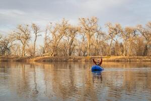 senior male is paddling an inflatable packraft on a calm lake with heron rookery in early spring in northern Colorado photo