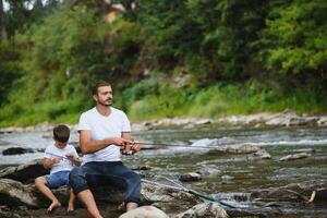 padre enseñando hijo cómo a pez volador en río foto