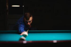 the player takes aim at the ball in Billiards photo