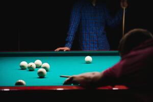 the player takes aim at the ball in Billiards photo